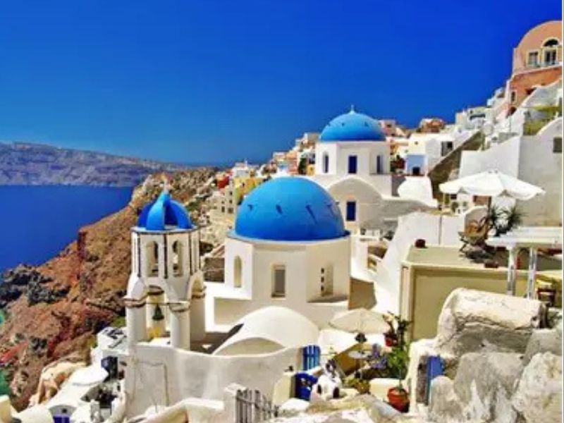 Bright sunny view of Santorini’s cliffside homes and blue sea — a serene island travel destination in Greece.