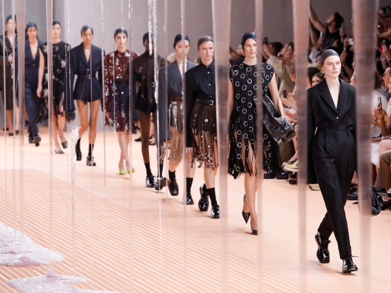 Close-up of models in couture attire on a sleek runway, emphasizing contemporary fashion and the glamour of global luxury travel events September